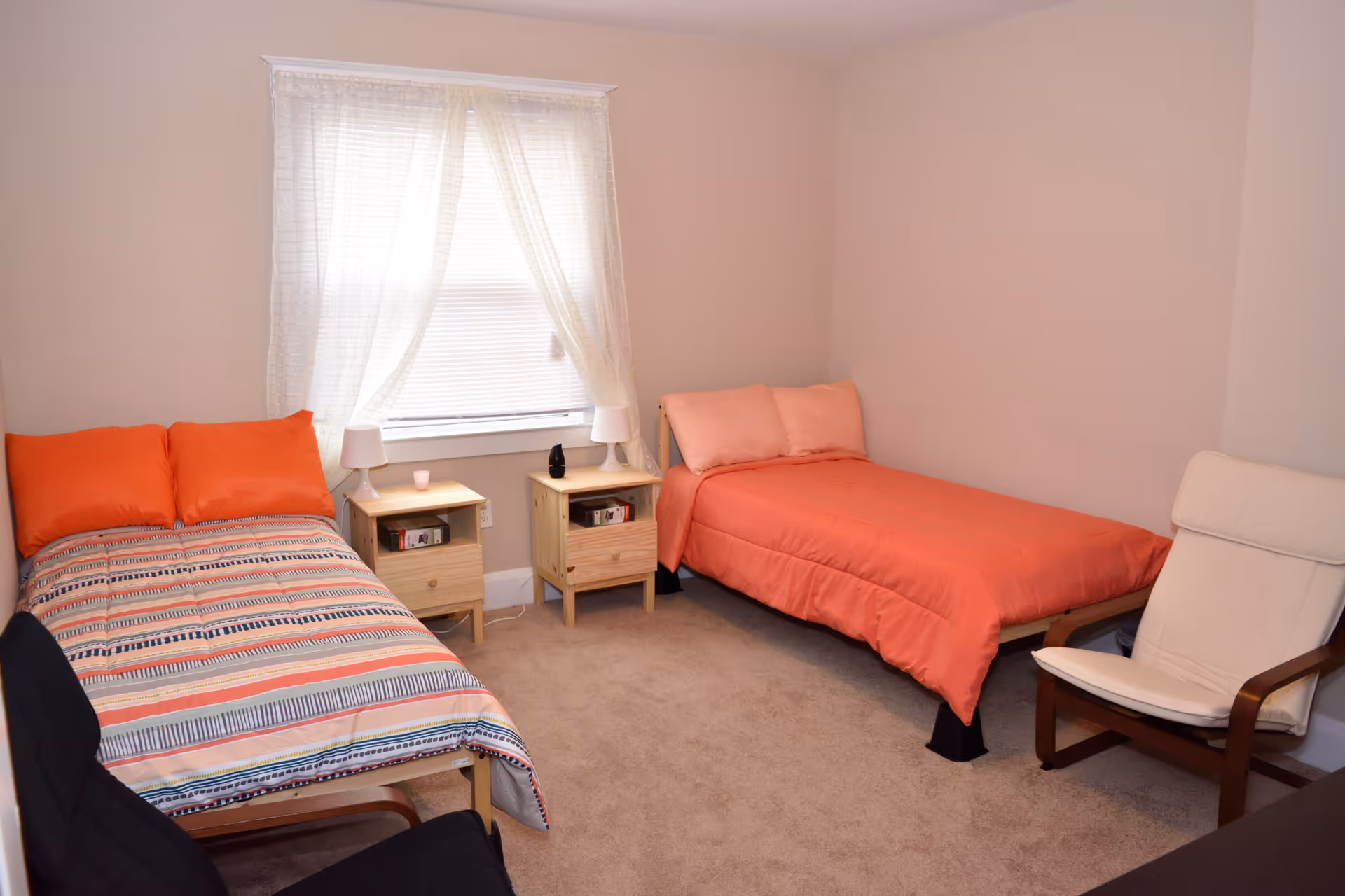 Two single beds with coral bedding and nightstands in a tidy bedroom.