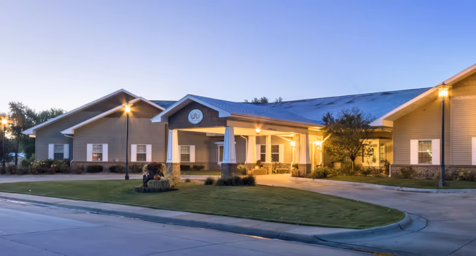 Front view of a Country Club senior living facility with a lit entrance and manicured landscaping.