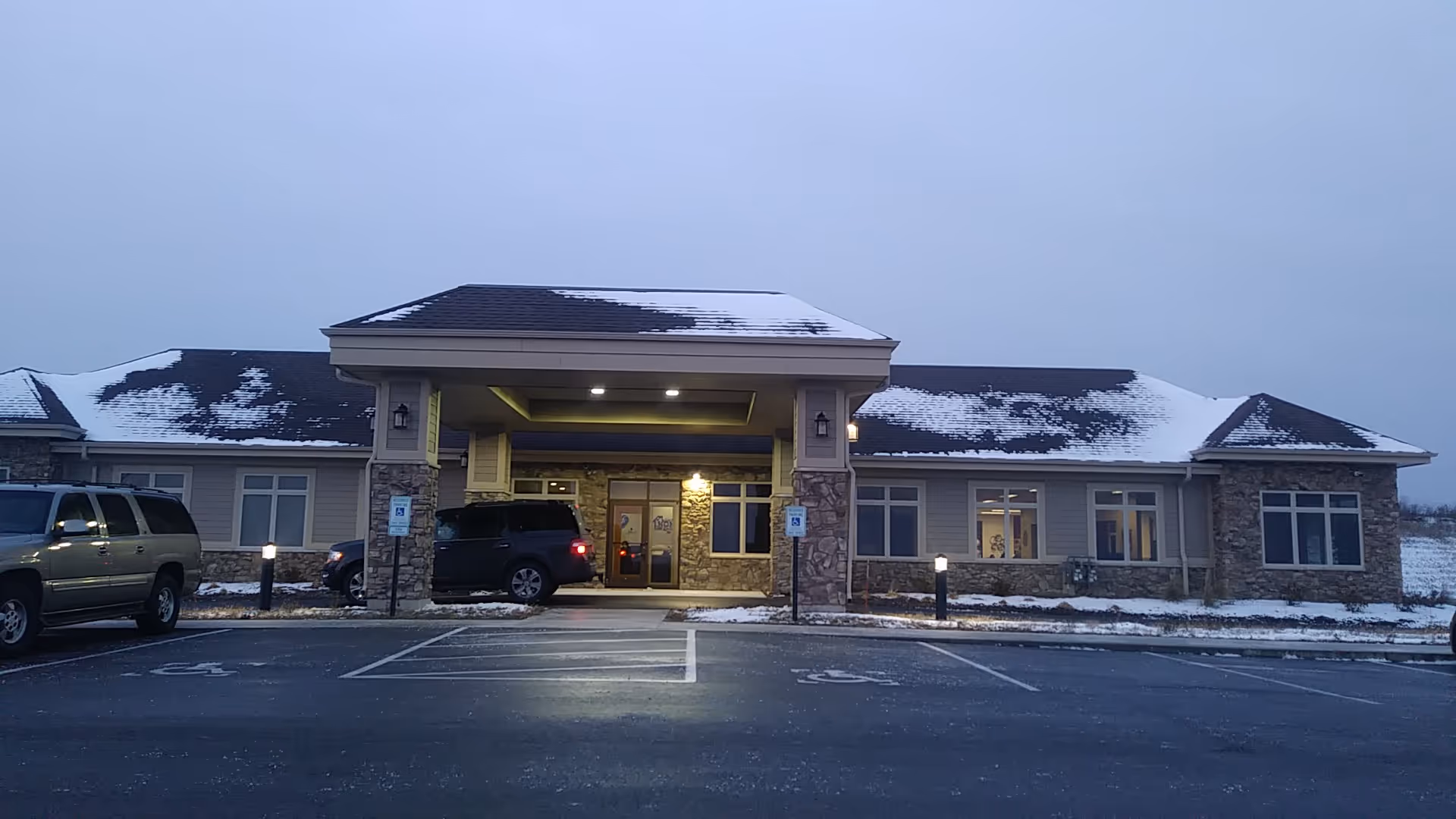 Front view of a single-story senior living facility with stone accents and snow.