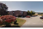 Exterior view of Riverside Rest Home showing brick building, parking lot and landscaping.