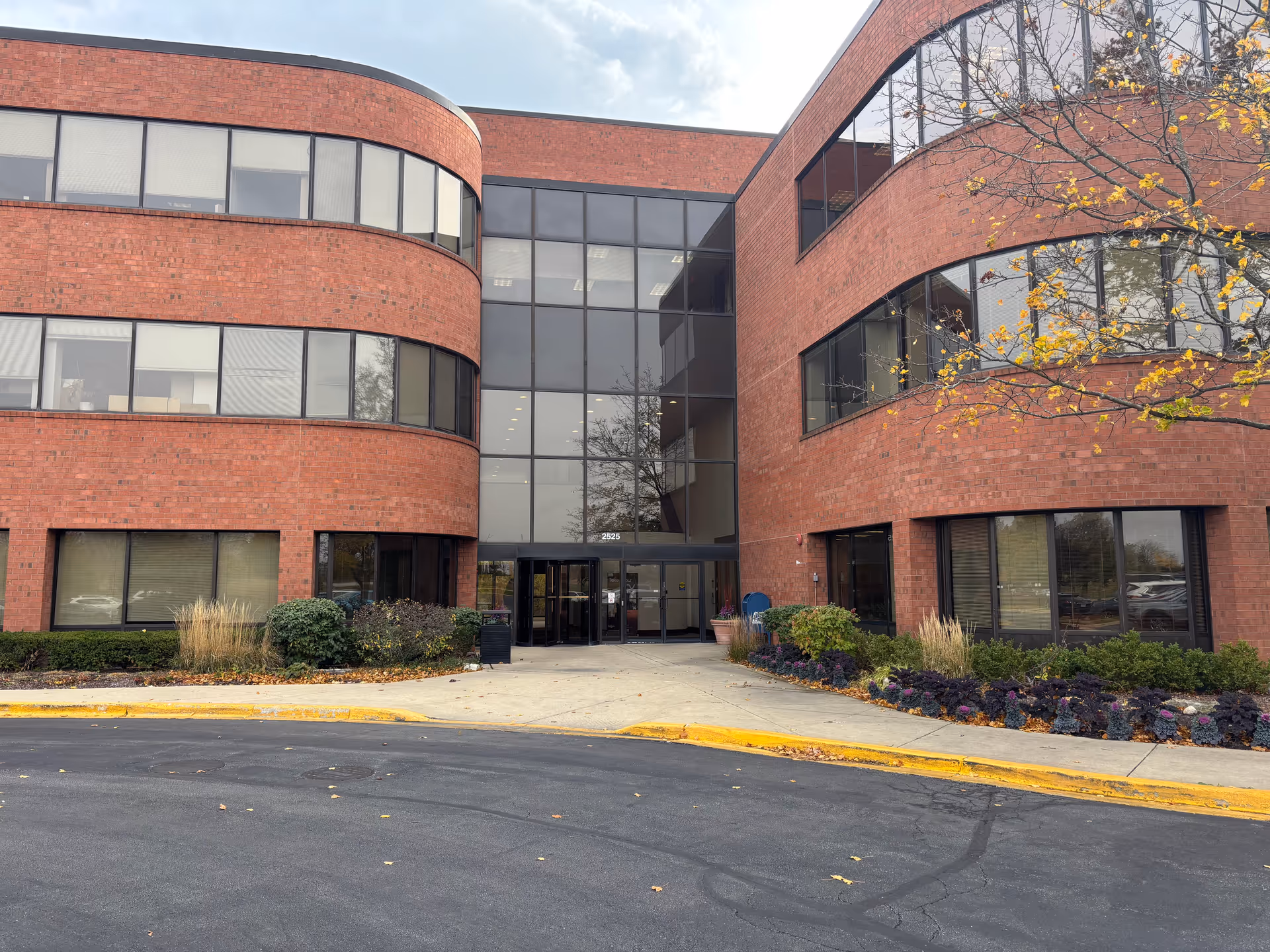 Brick exterior of a senior living facility with glass entry and landscaped frontage.