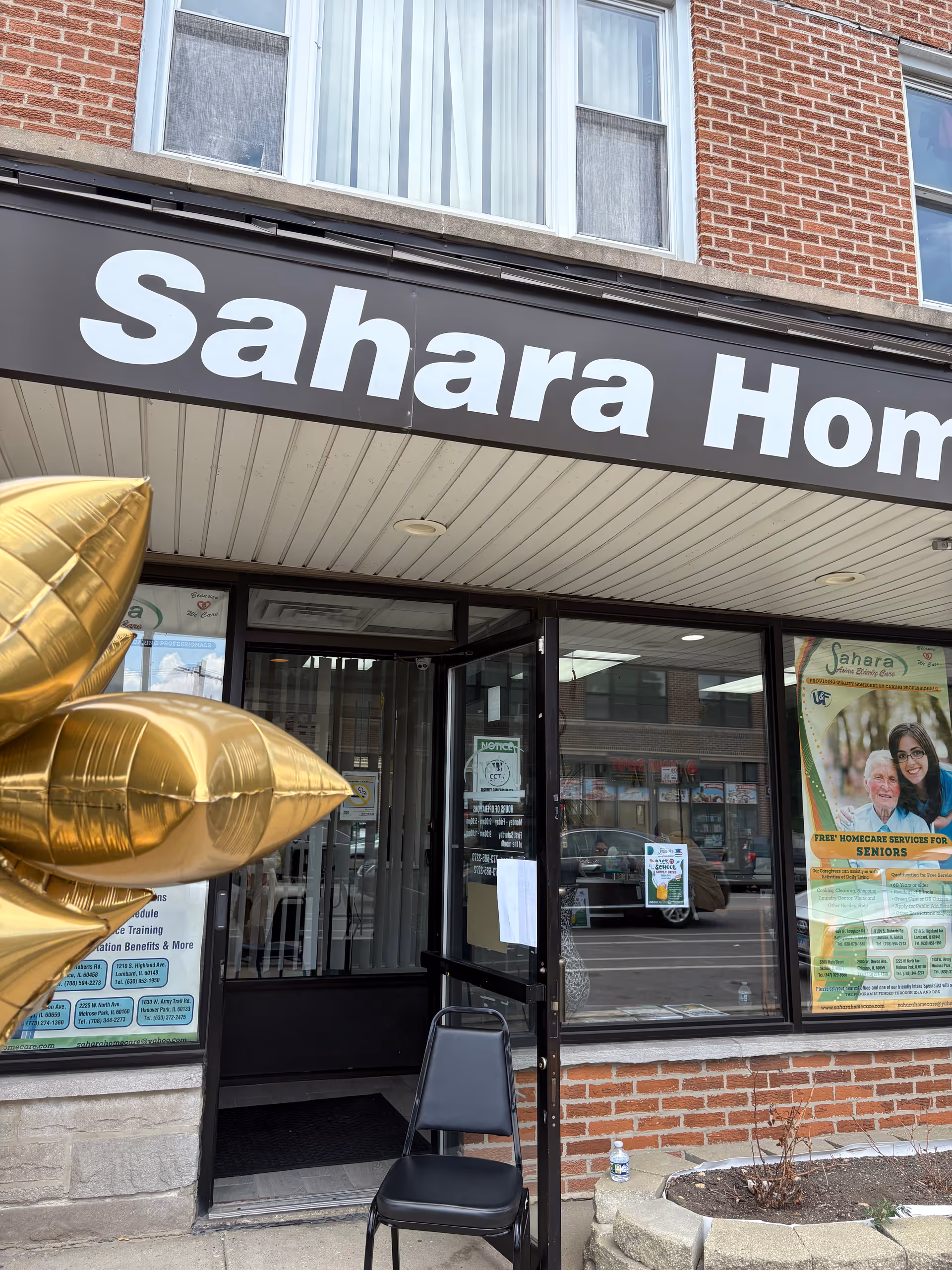 Front of Sahara Home Care storefront with large sign, glass doors, and a black chair outside.