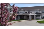 Exterior view of Ballard Creek Community with curved driveway and pink flowering tree in foreground