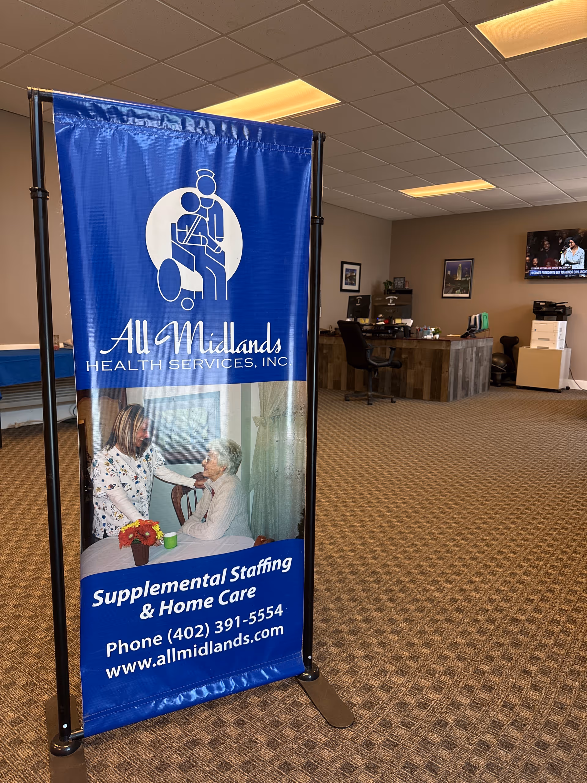 Blue All Midlands banner stands in a clinic lobby with a reception desk.