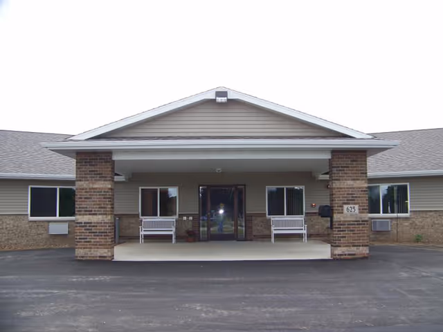 Front entrance of Rose Assisted Living Facility, LLC with brick columns and benches.