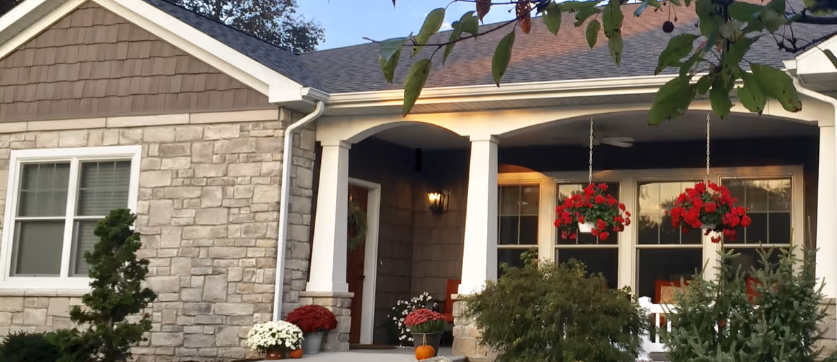 Stone facade building with a covered front porch and hanging flower baskets.