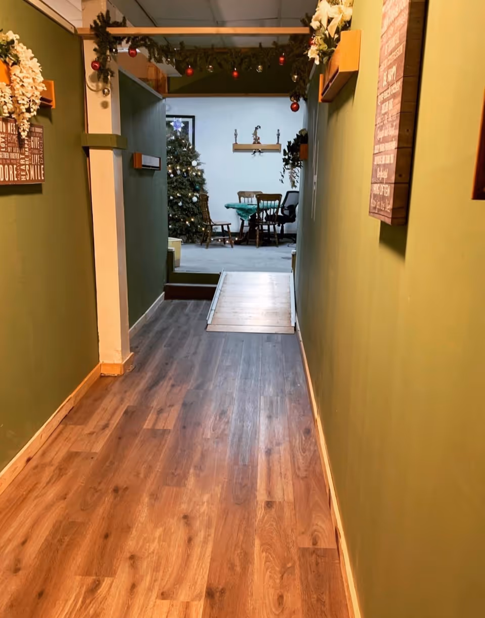 Hallway inside Verna's House decorated for Christmas, leading to a dining area with a table.