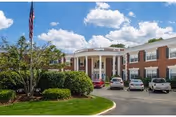 Exterior view of Grosvenor Park Healthcare, brick building with curved entrance and parking.