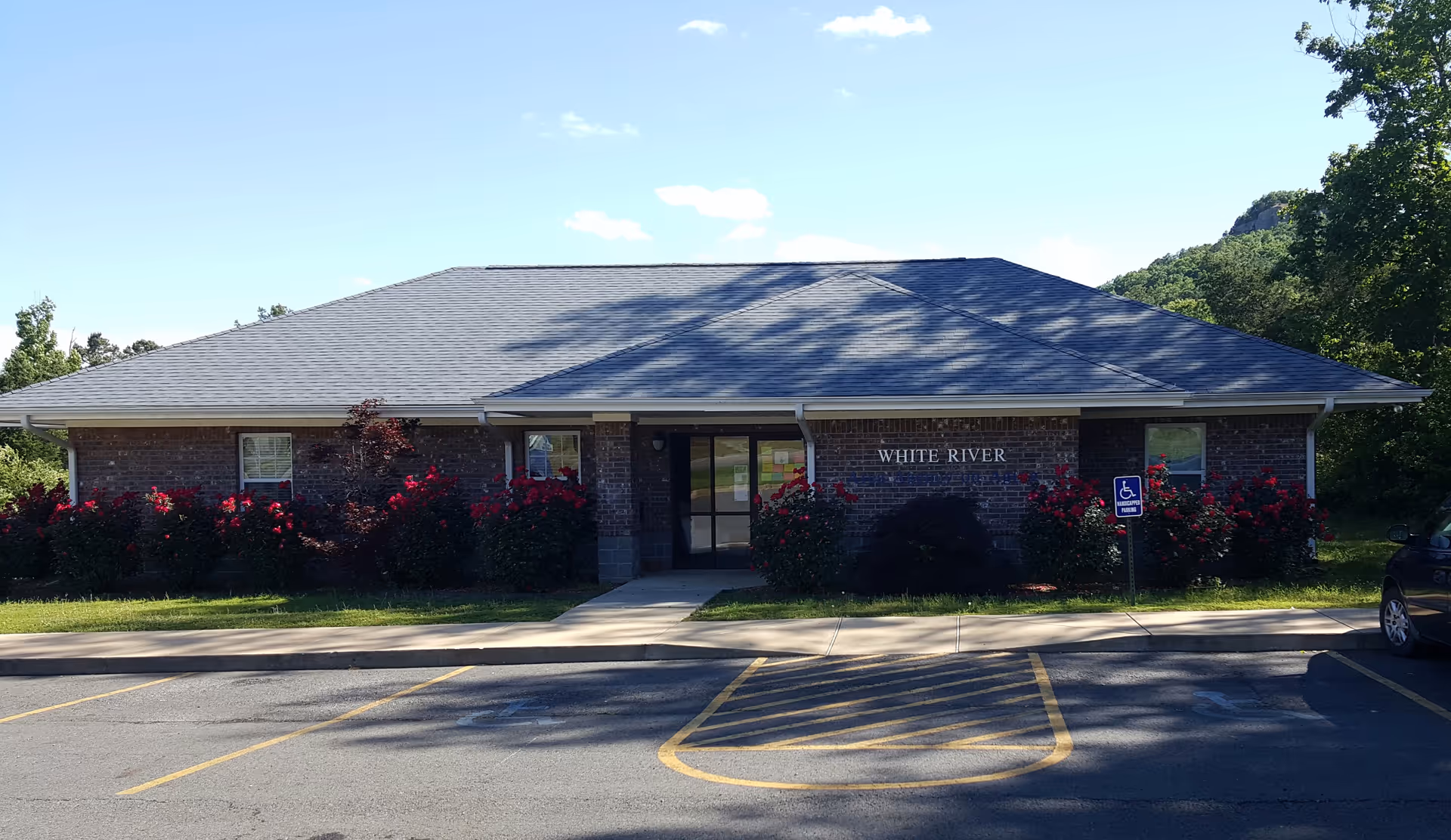 Brick facility front with a sloped roof, shrubs, and visible White River signage