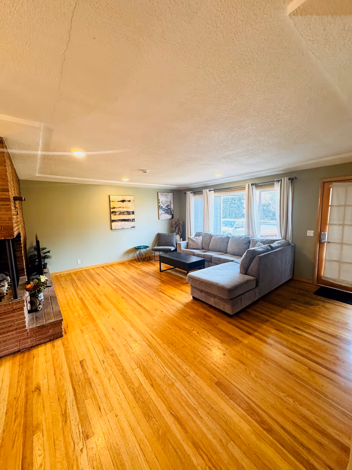 Spacious living room with gray sectional sofa, coffee table, fireplace, and large windows