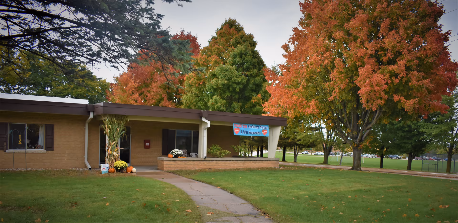 Front of Greentree Health and Rehab Center, a single-story building with a walkway and fall trees.
