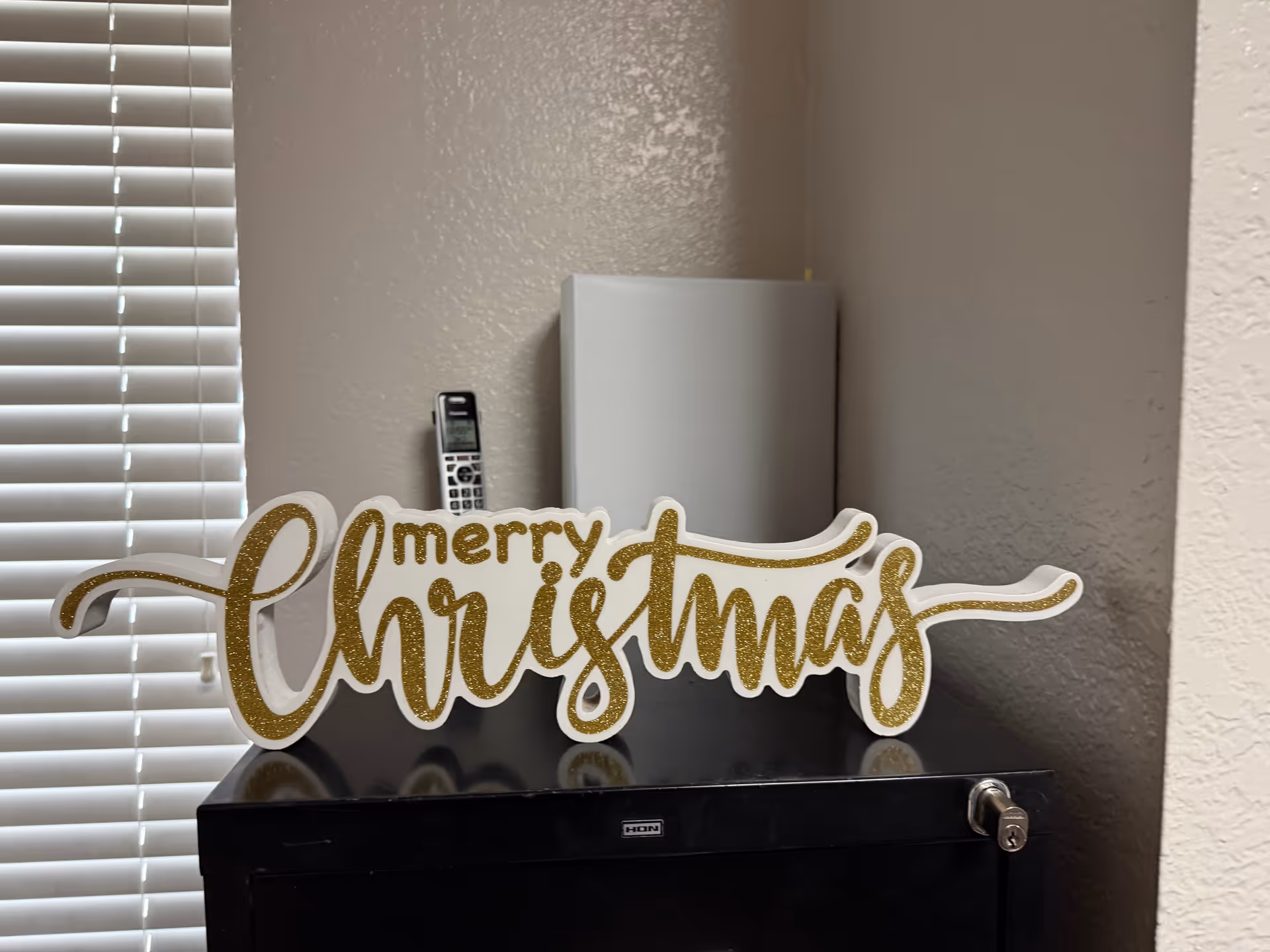 Indoor corner with a glittery Merry Christmas sign on a dark cabinet.
