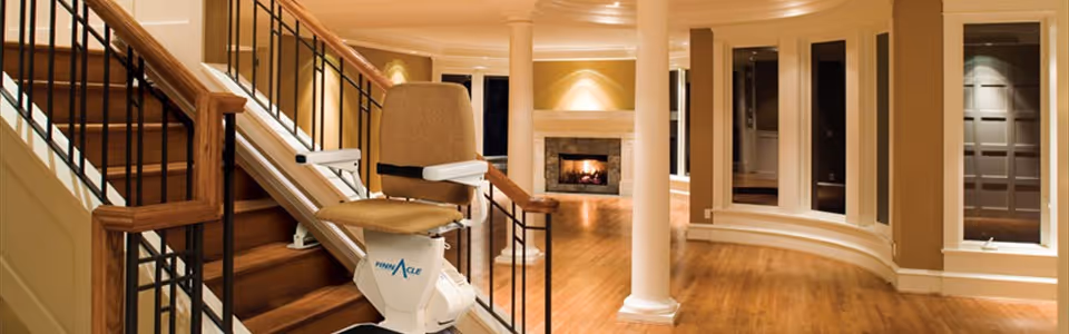 Interior view of a warm lounge with a fireplace, curved wall alcoves, and a stairlift chair.