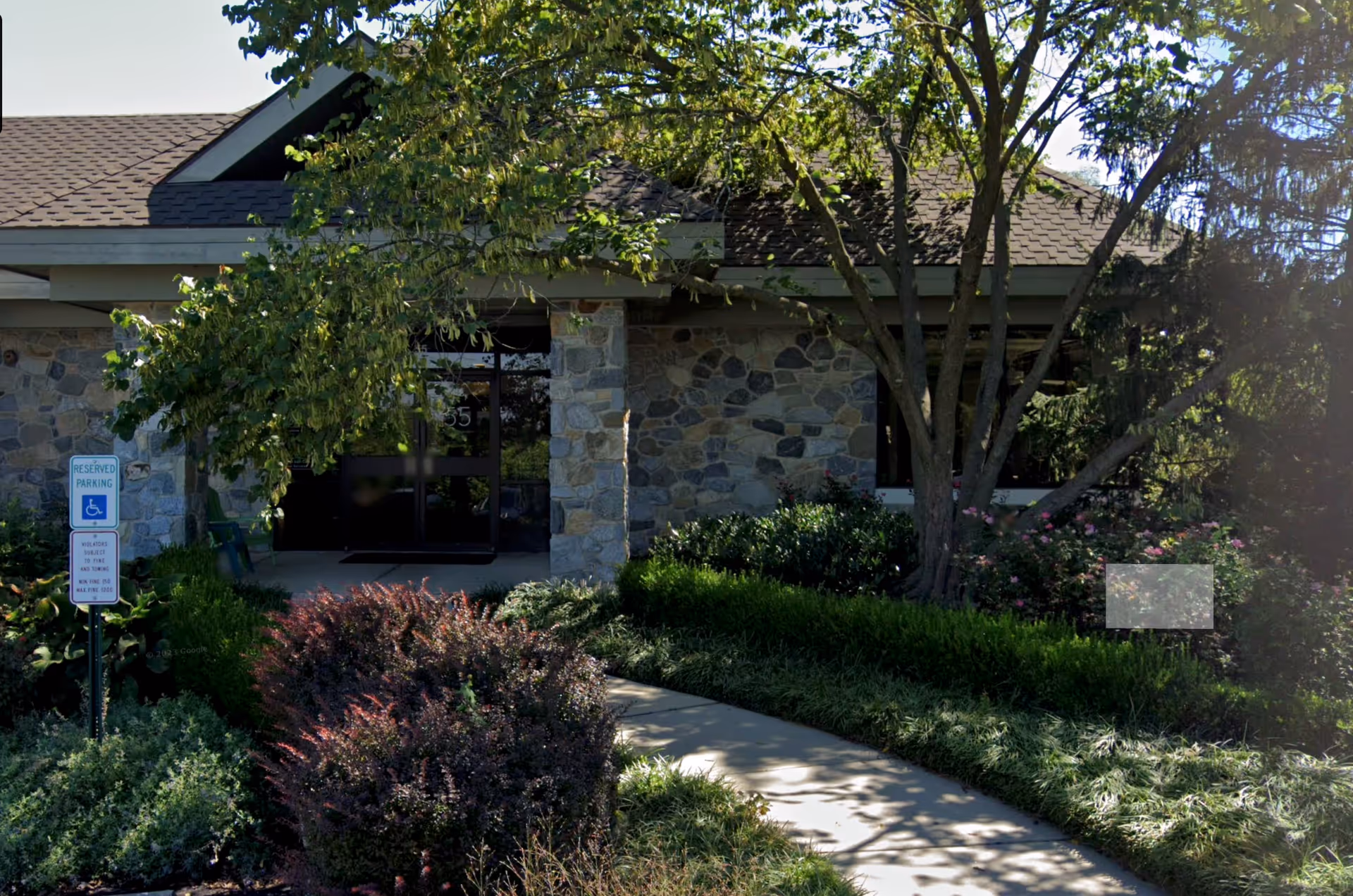 Senior care facility entrance with stone exterior and landscaped walkway.