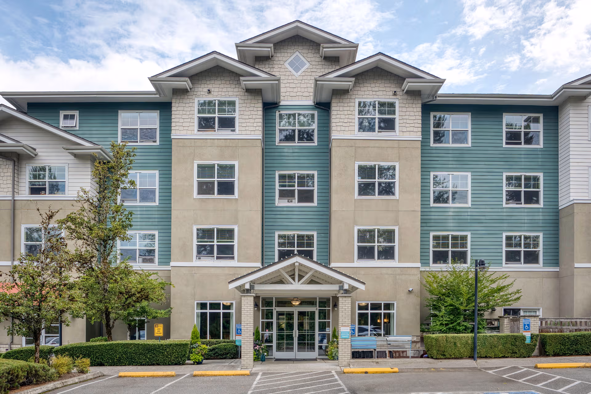 Exterior view of The Creekside senior living building with teal and beige siding.