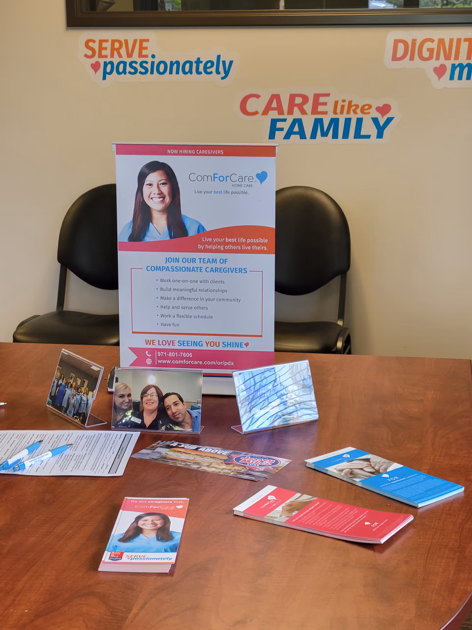 Interior reception area with chairs, brochures, and posters on a wooden table.