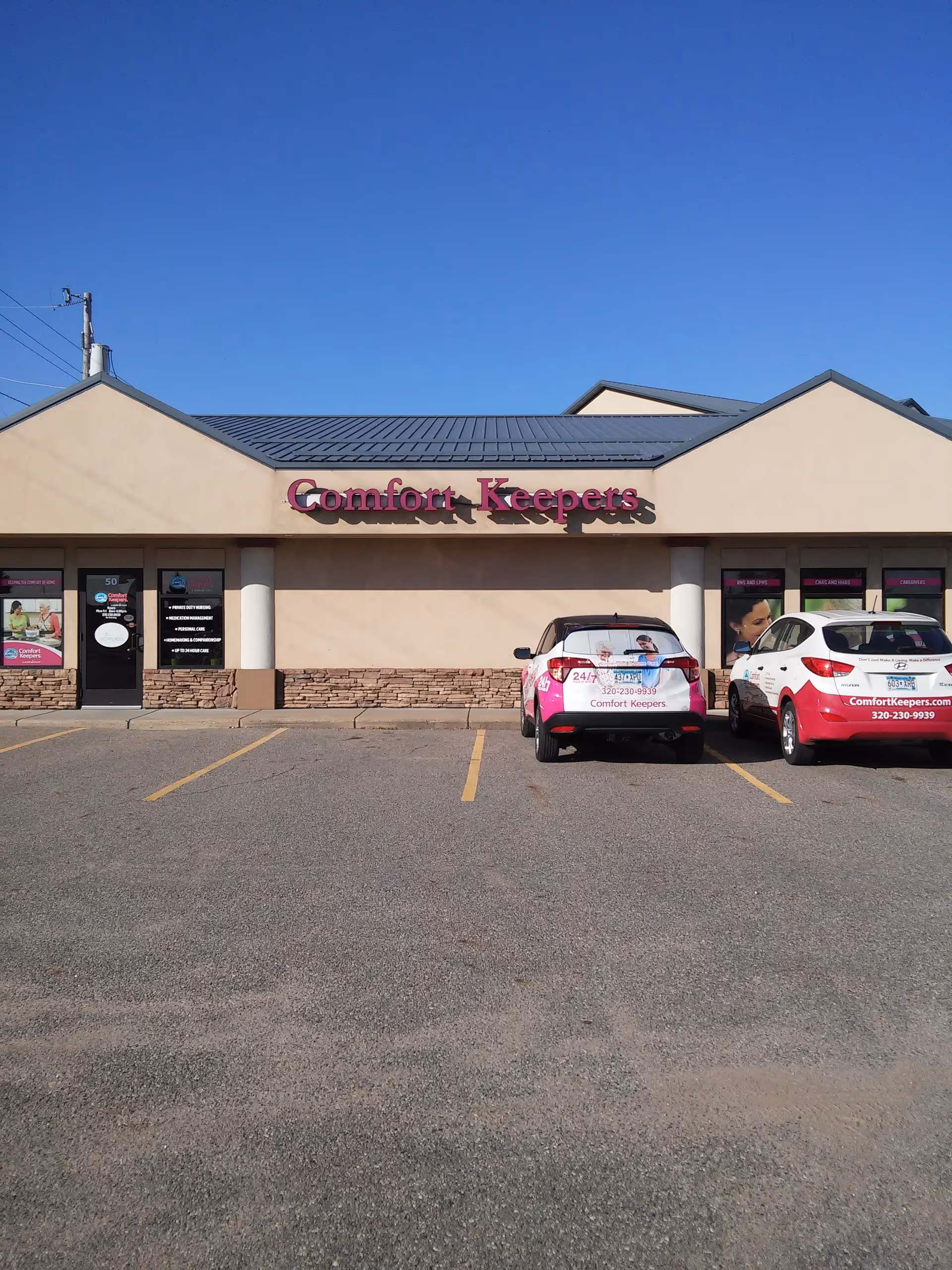 Front of Comfort Keepers facility with parked company cars in the lot.