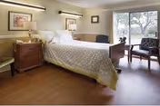 Bright bedroom with a large bed, nightstands, chairs, and a window view.