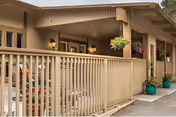 Exterior view of Windsor Monterey Care Center entrance with railing and potted plants.
