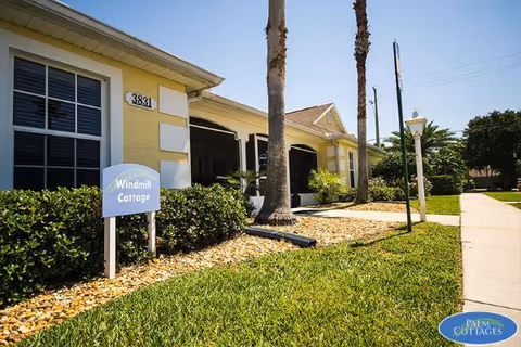 Exterior view of Hill Top Home of Comfort building with palm trees and signage.