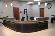 Curved reception desk in a bright lobby with pendant lights and clock.