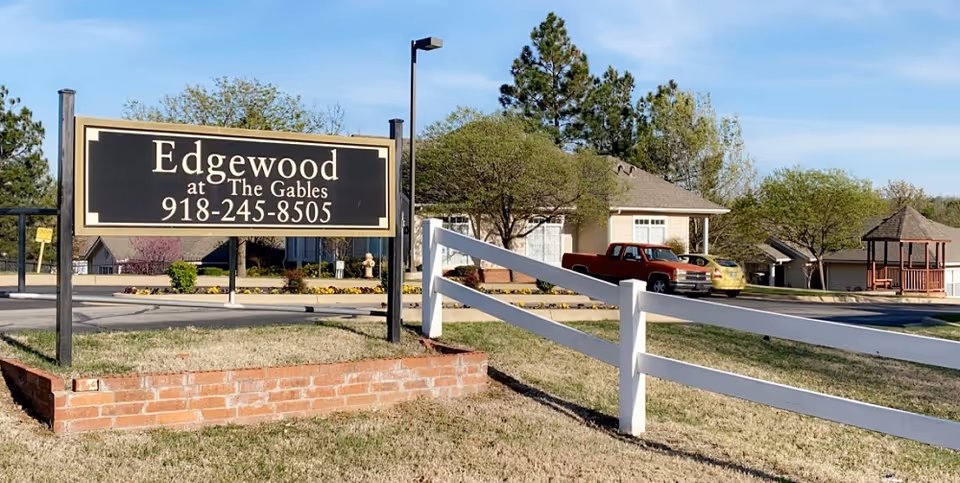 Edgewood at The Gables sign on a brick planter with a white fence