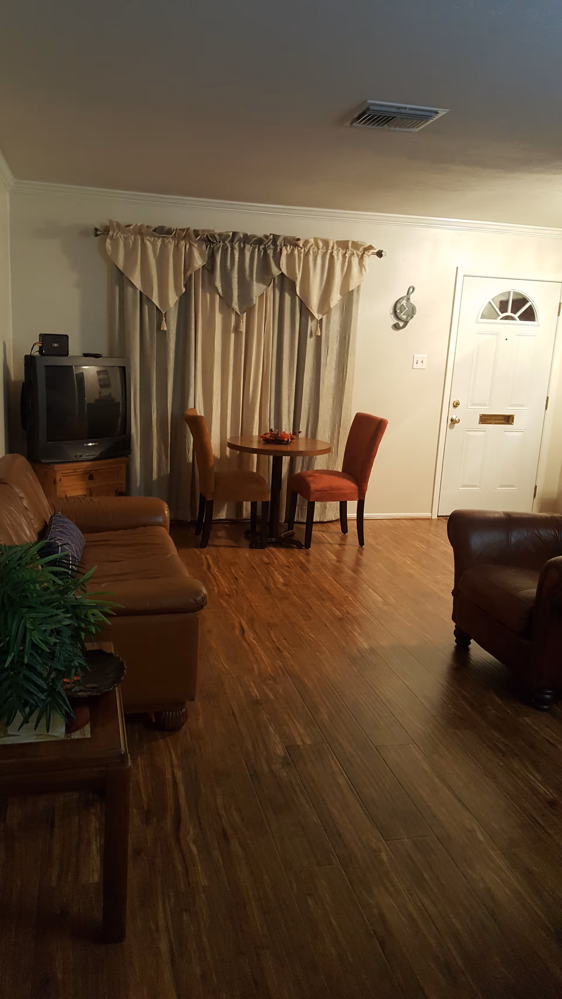 Cozy living room with sofa, small dining table, TV, and front door.