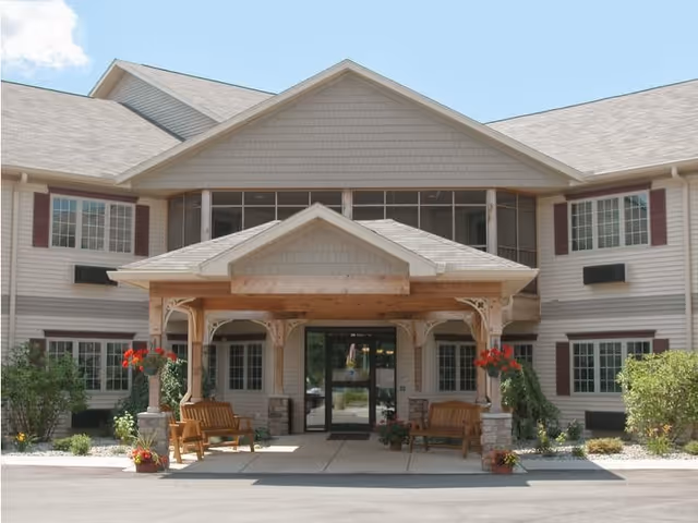 Front exterior of Miller's Senior Living Community with covered entrance, benches, and flower planters.