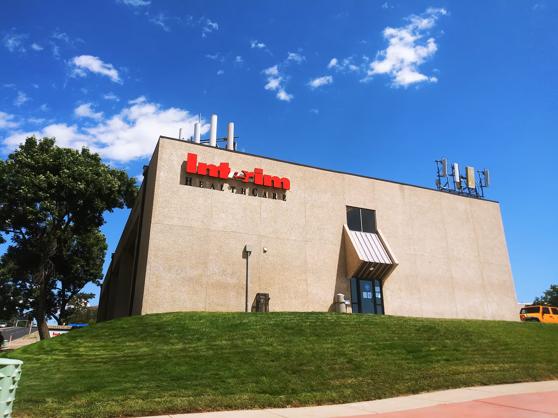 Exterior view of Interim Healthcare building with blue sky and green lawn in foreground.