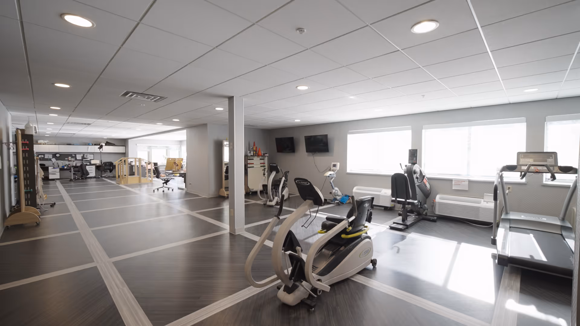 Bright senior living fitness center with cardio machines and an open layout.