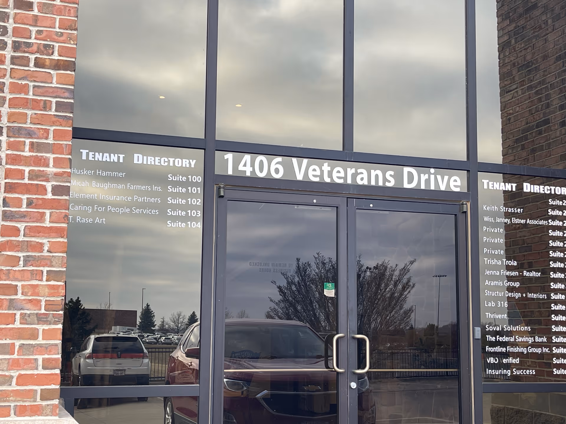 Entrance with glass doors, brick facade, and a tenant directory showing 1406 Veterans Drive.
