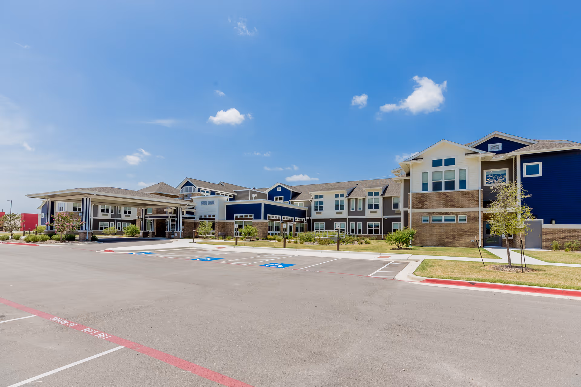 Modern senior living facility exterior with blue and gray siding and parking lot