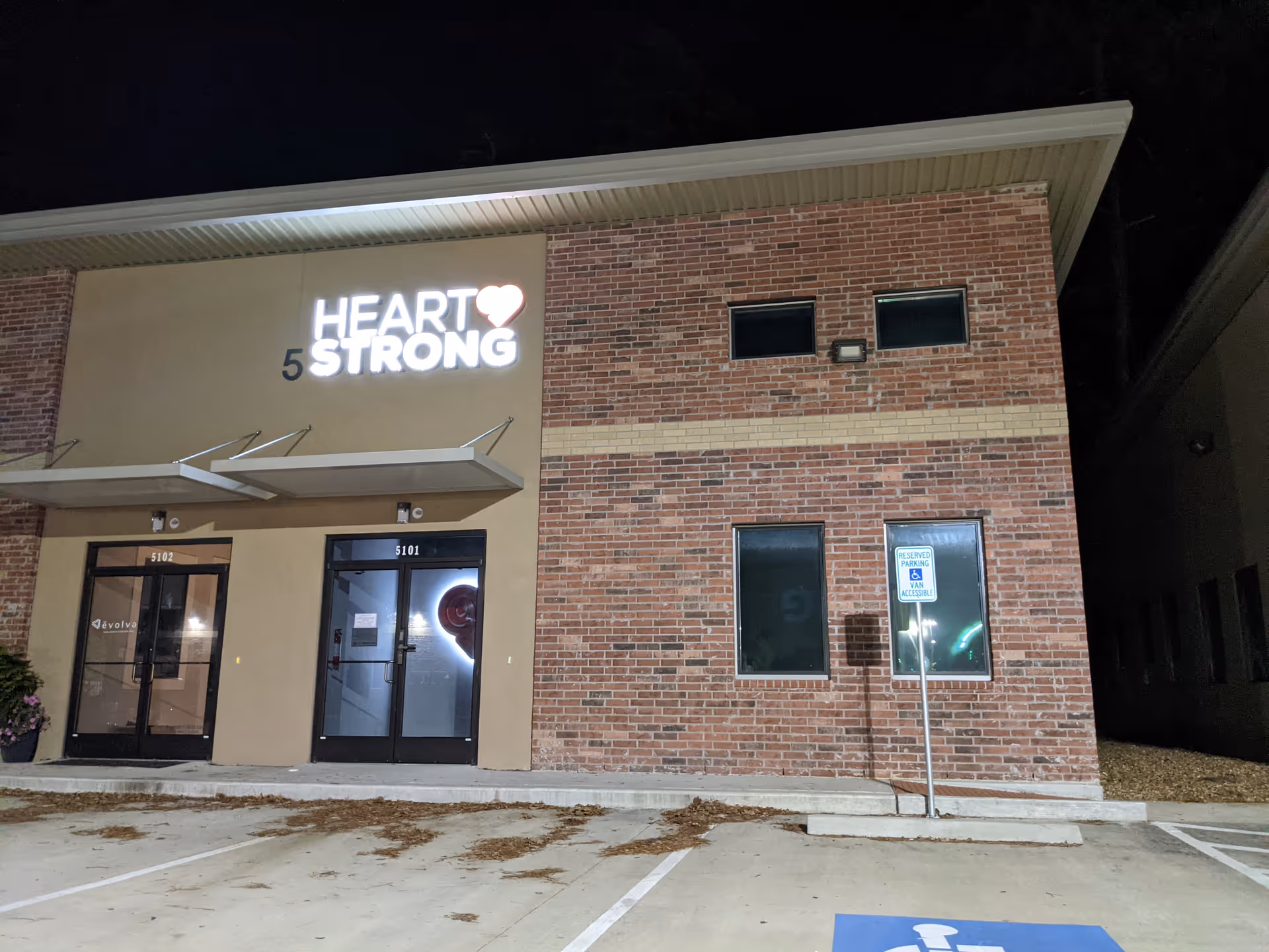 Night exterior of Heartstrong Sleep facility with brick facade and illuminated sign.