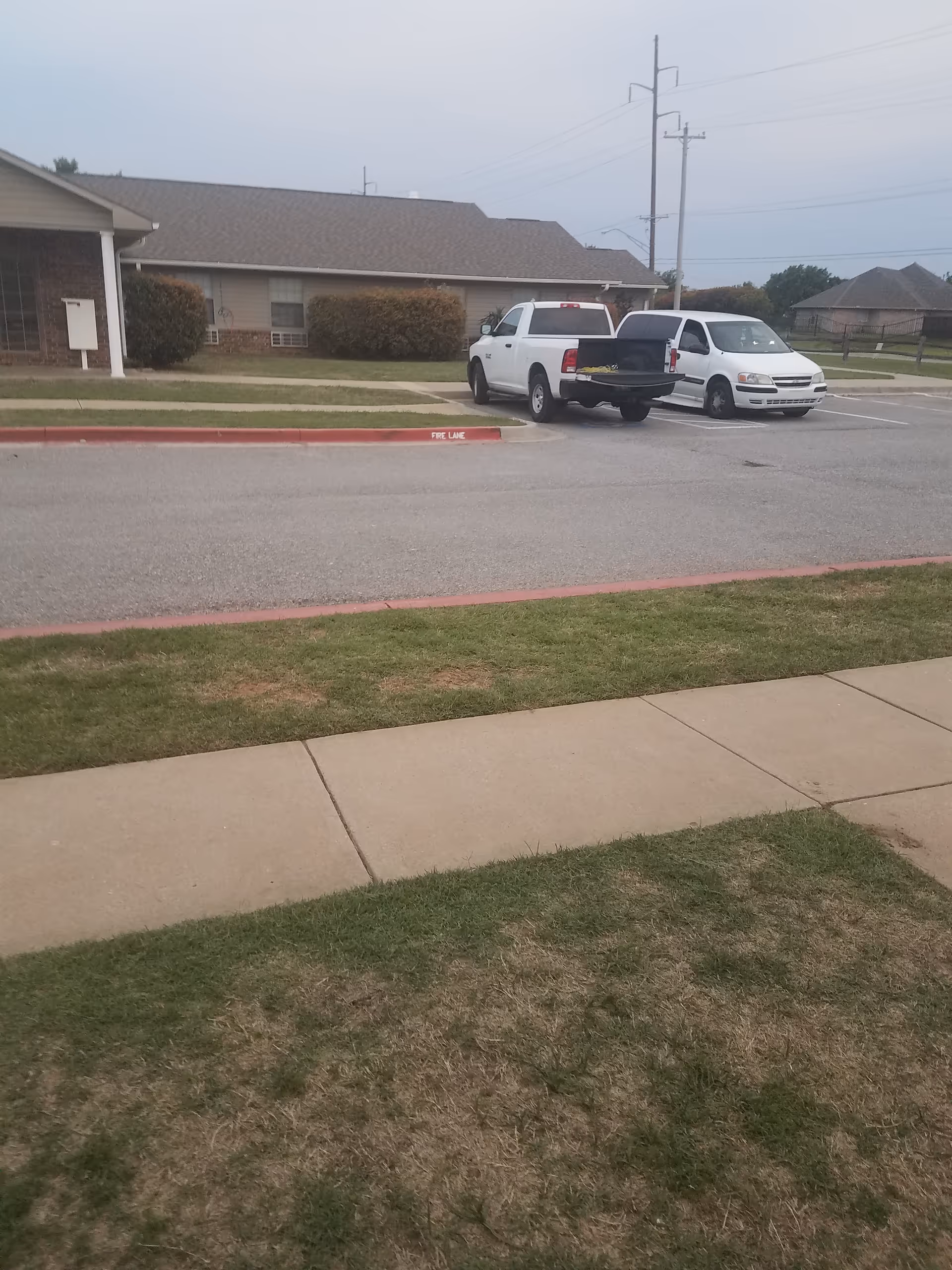 Two white vans parked in a lot beside a single-story facility.