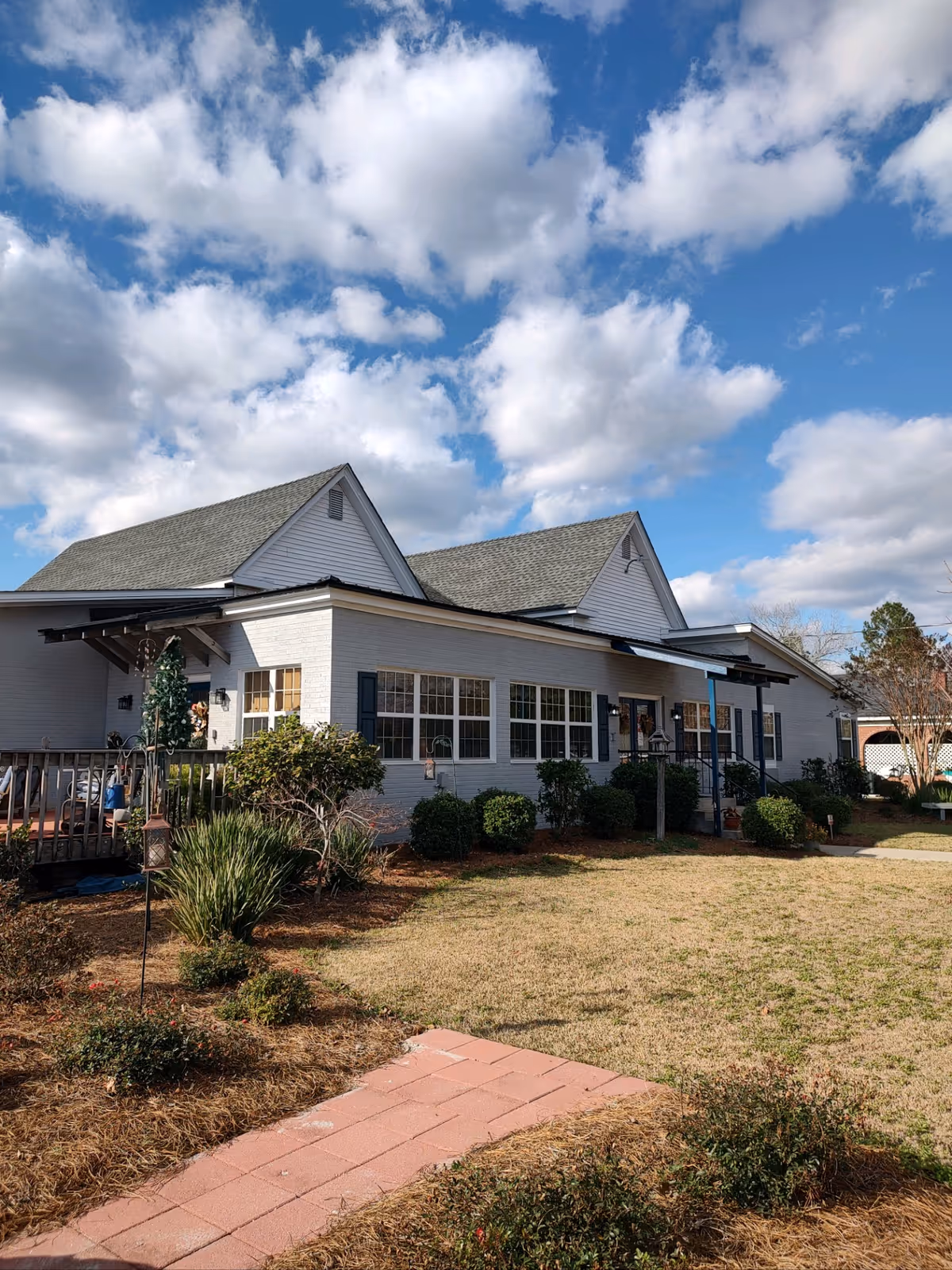 Single-story white-brick senior living facility exterior with windows and landscaped lawn.