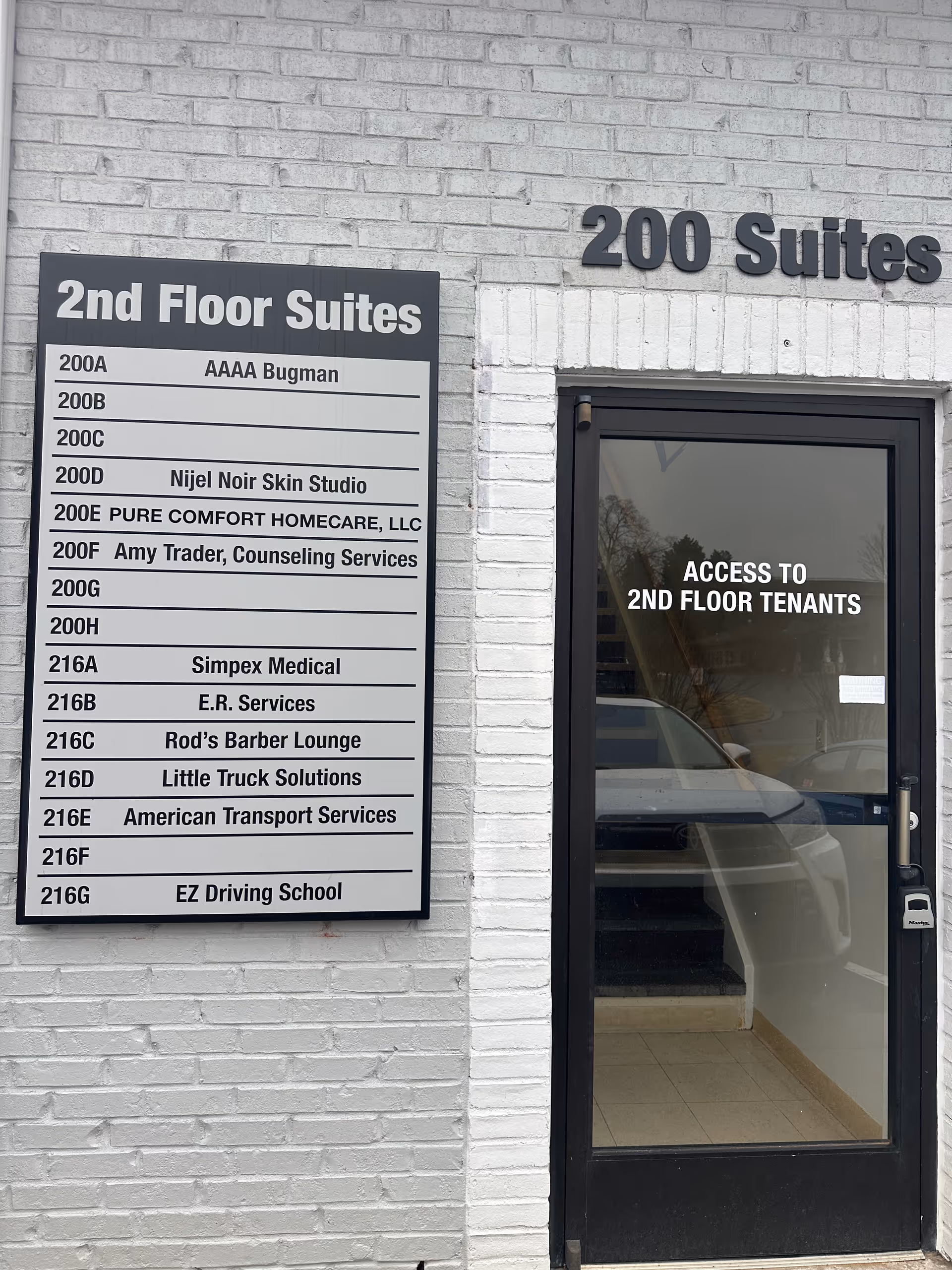 White brick exterior with a directory sign listing Pure Comfort Homecare LLC and suites.