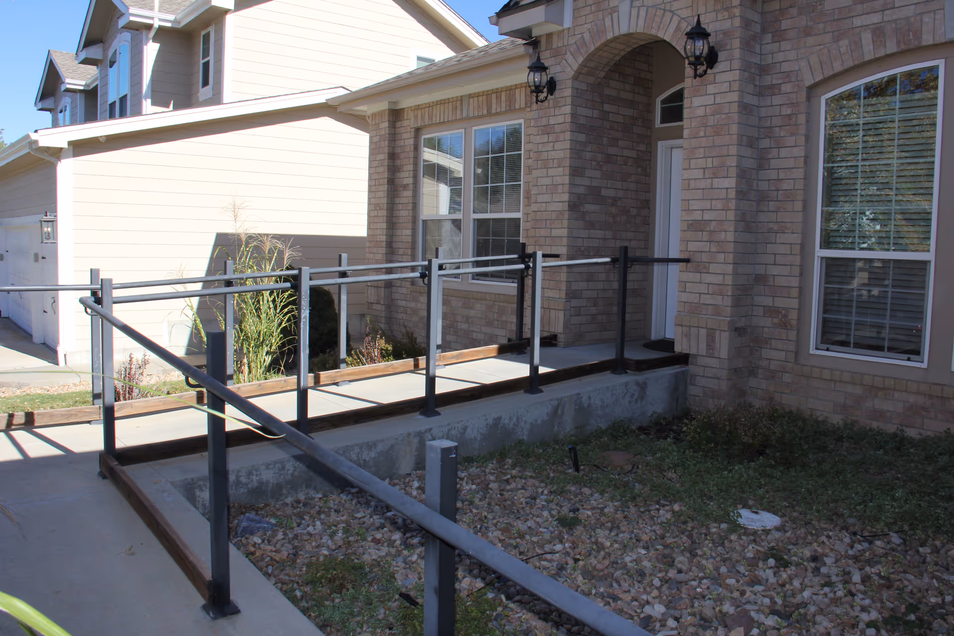 Brick facility entrance with accessible ramp and railing leading to a covered doorway under arches.