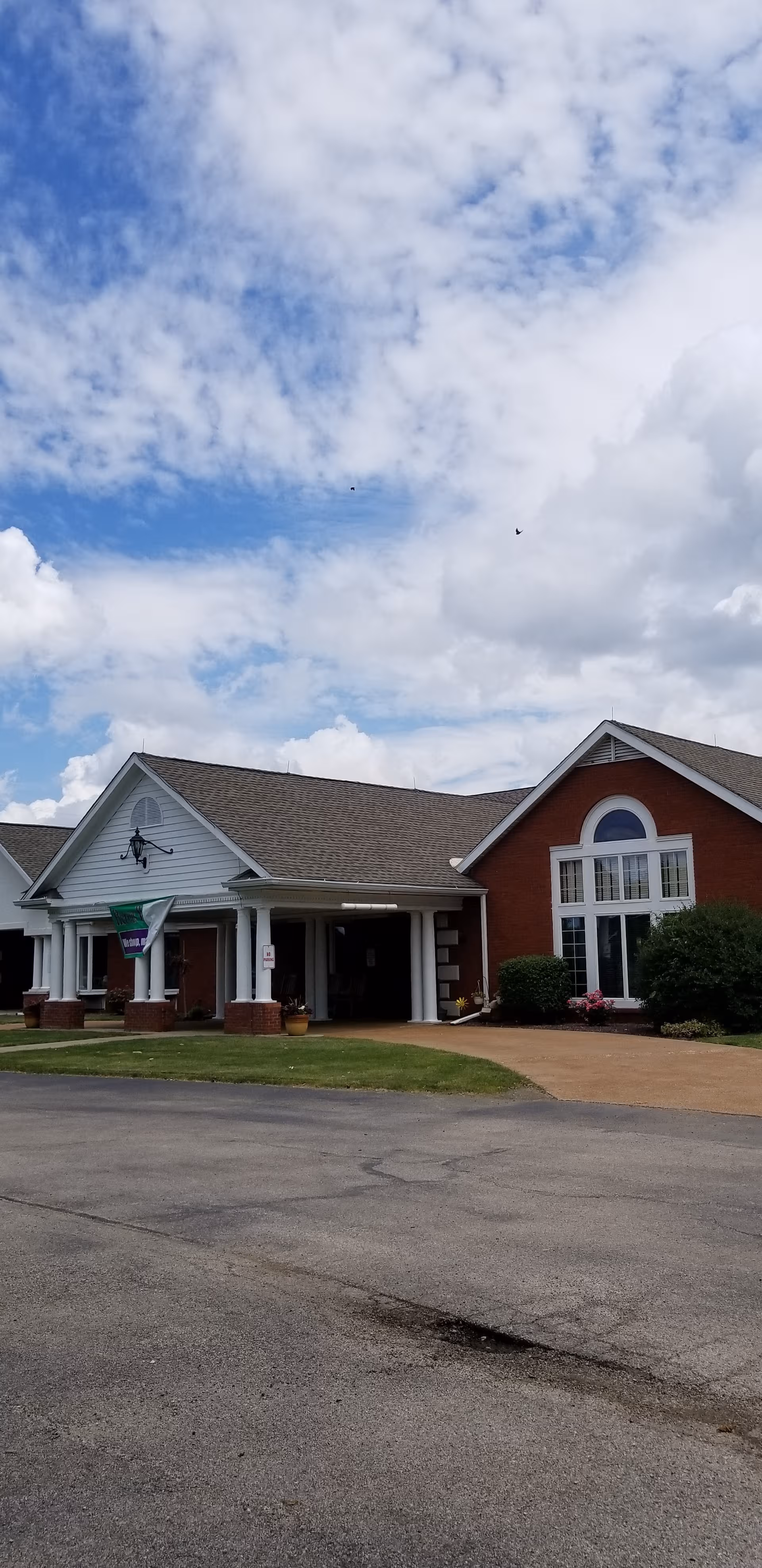 Exterior view of Seminary Village facility with brick facade, columns, and a clear sky.