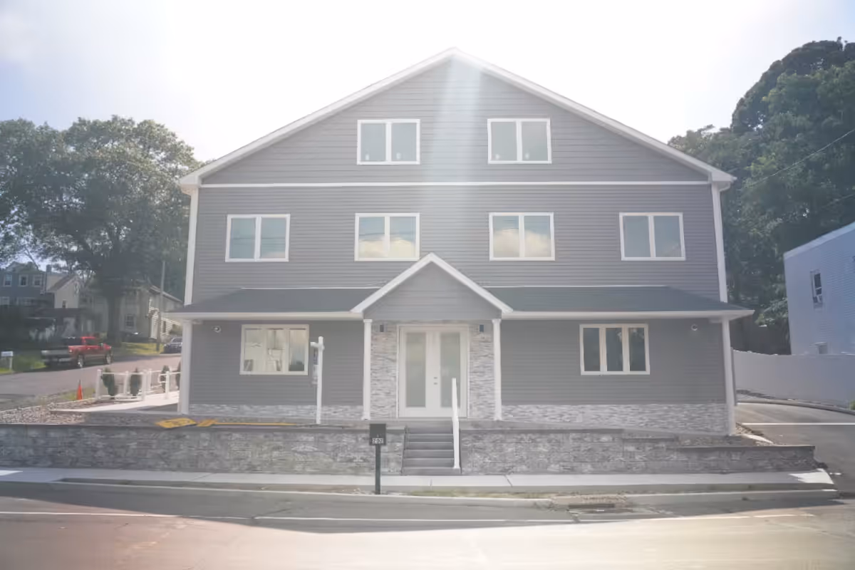 Gray multi-story facility exterior with a covered entrance and stone base.