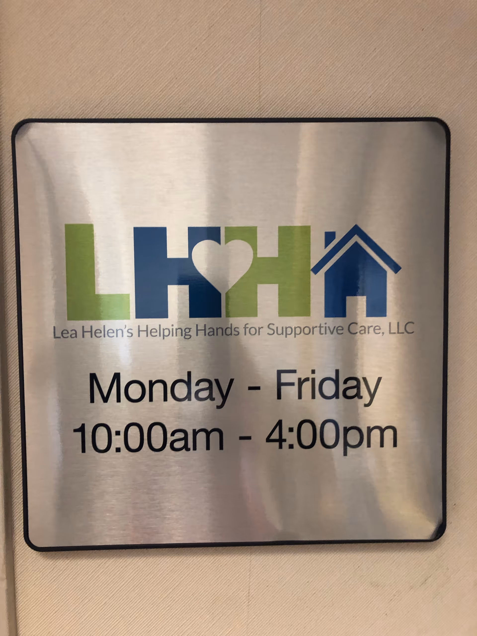 Metal wall sign showing Lea Helen's Helping Hands logo and hours.