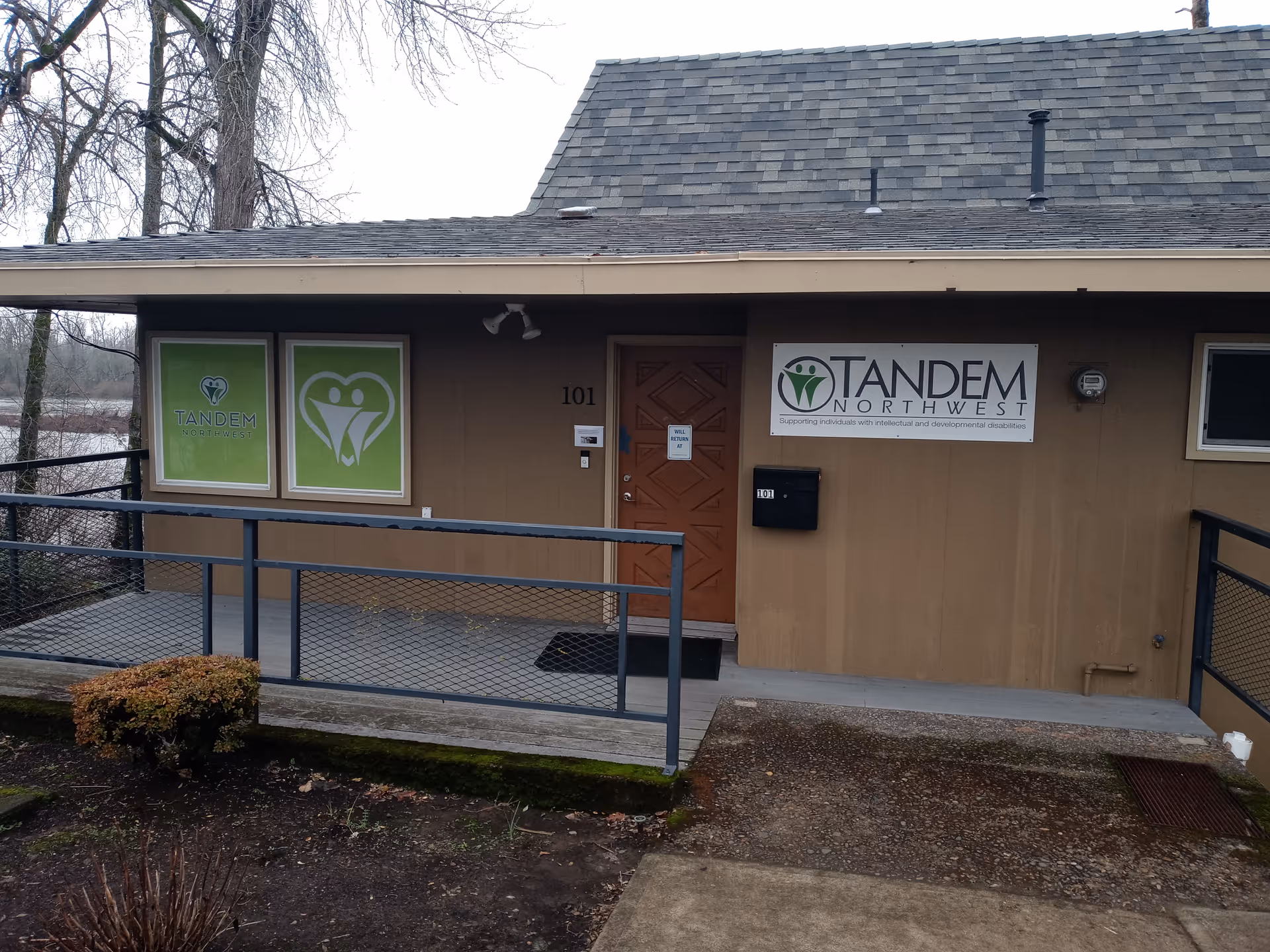 Exterior view of Tandem Northwest facility entrance with brown siding, ramp, and signage.