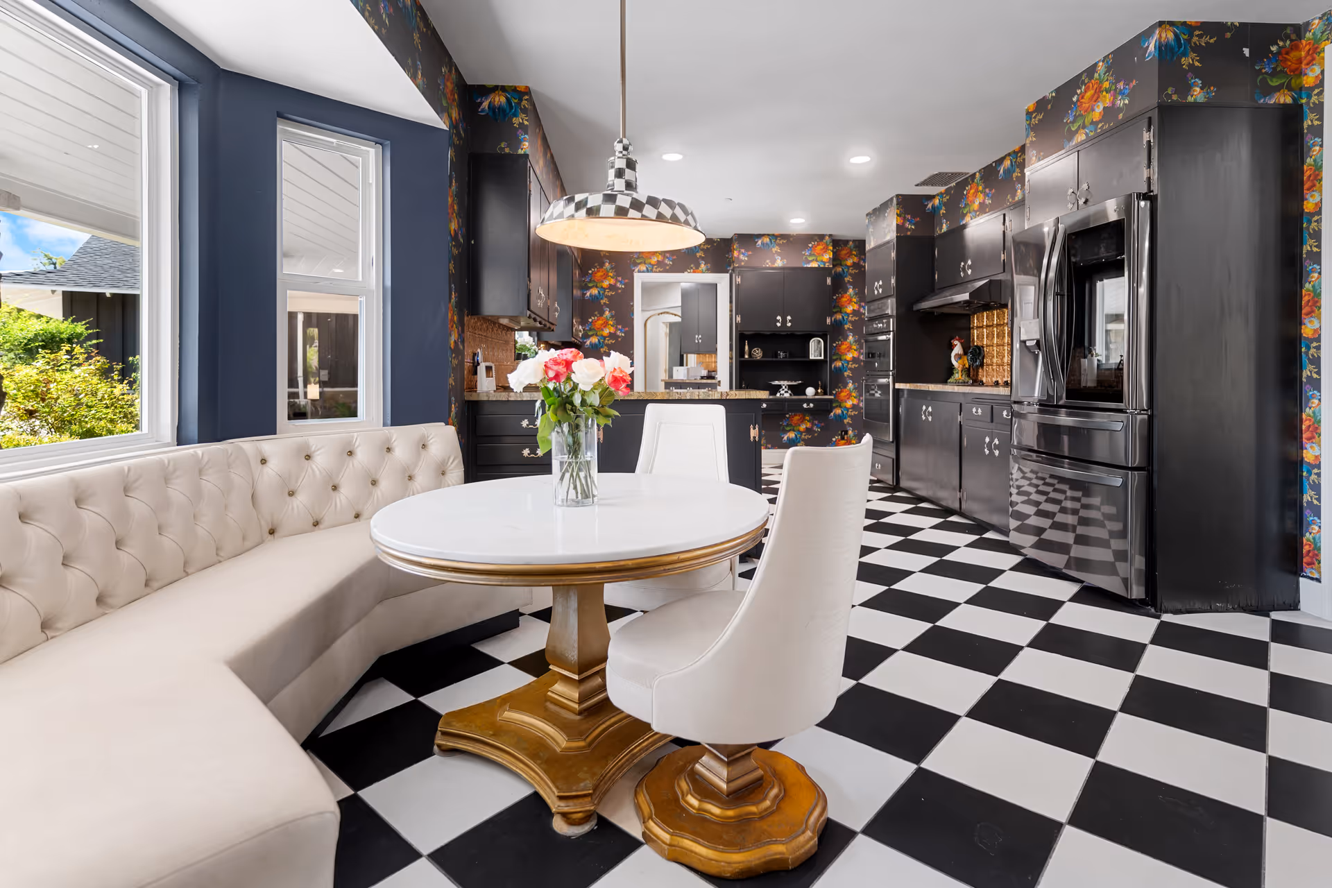 A stylish dining area with a round white table, tufted bench seating, and black-and-white checkered floor.