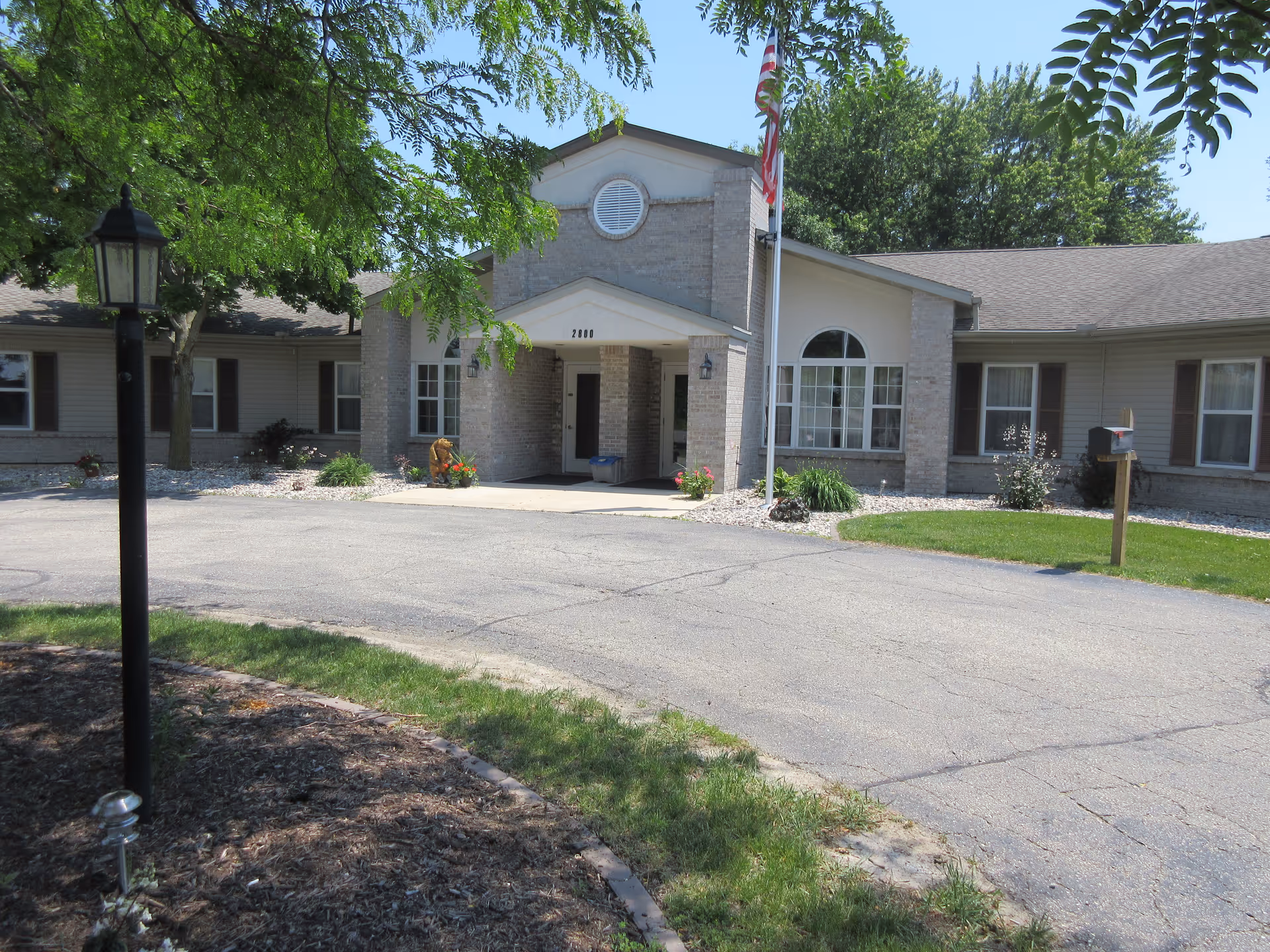 Front exterior of Dimensions Living Monroe facility with entrance and flagpole