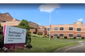 Brick building of Southington Care Center with sign, lawn, and blue sky.