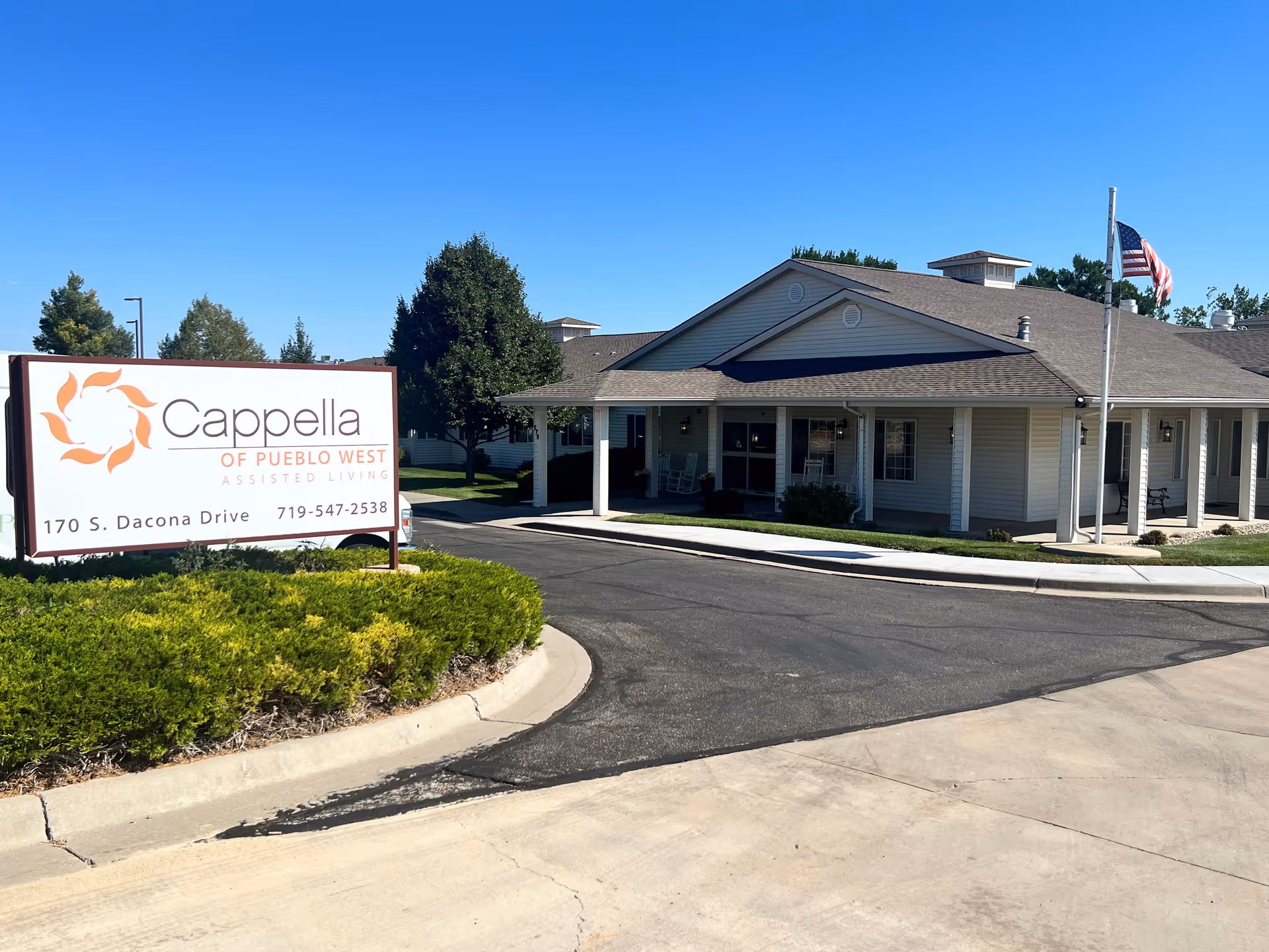 Exterior view of Cappella of Pueblo West with sign, entrance, and American flag.