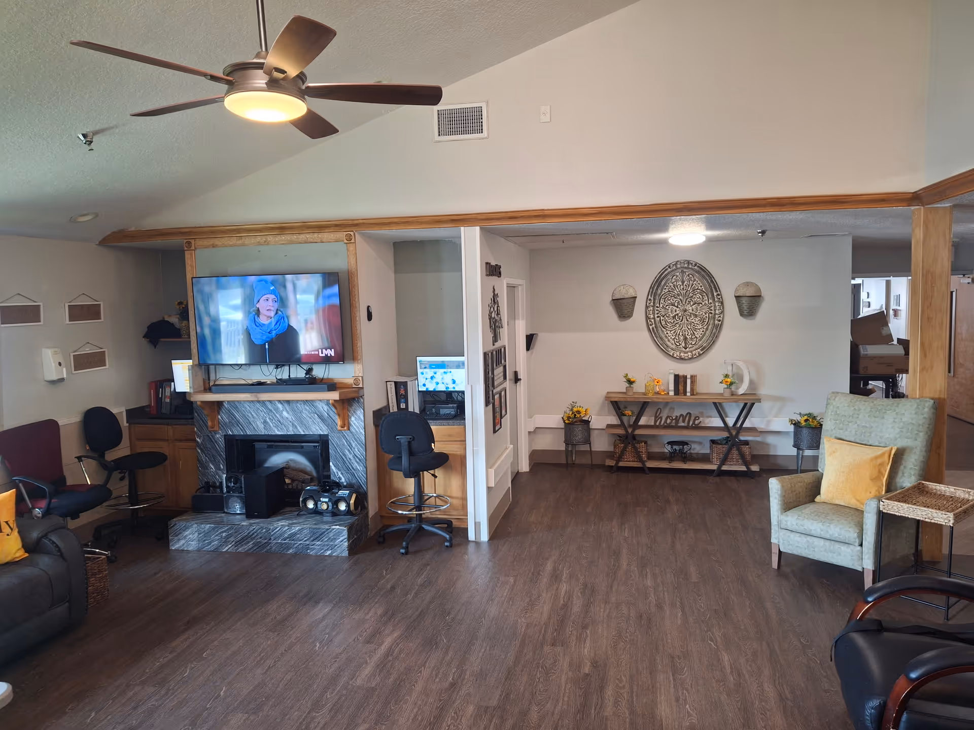 Cozy senior living common room with fireplace, mounted TV, seating, and decorative table.