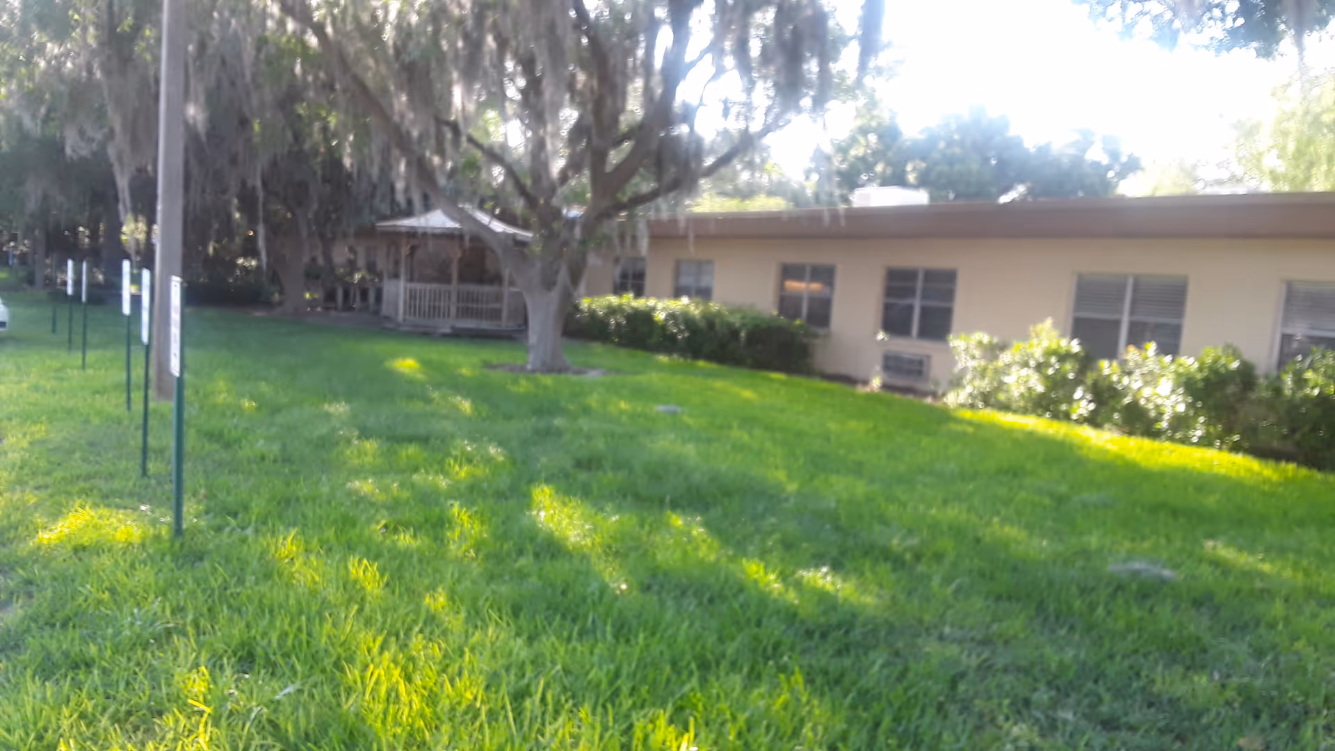 Lush green lawn surrounds a single-story hospice building with a gazebo.