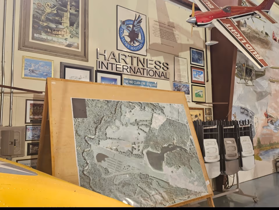 Museum-style room displaying aviation memorabilia, framed posters, model aircraft, and a large map.