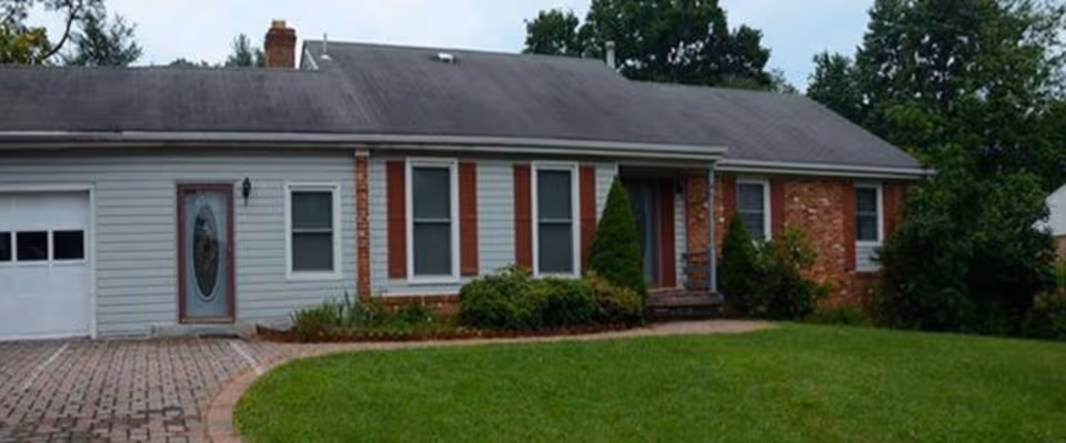 Single-story assisted living facility exterior with brick accents and a manicured lawn.