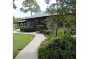 Sunlit exterior of Sunnyside Village with a curved walkway and landscaped front yard.